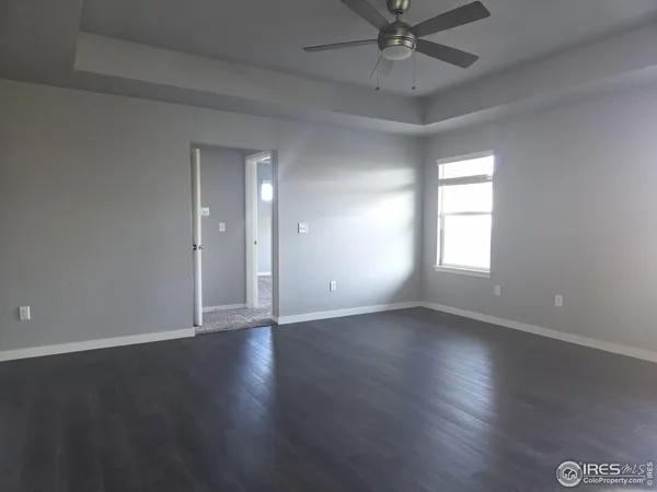 an empty room with wooden floor fan and windows