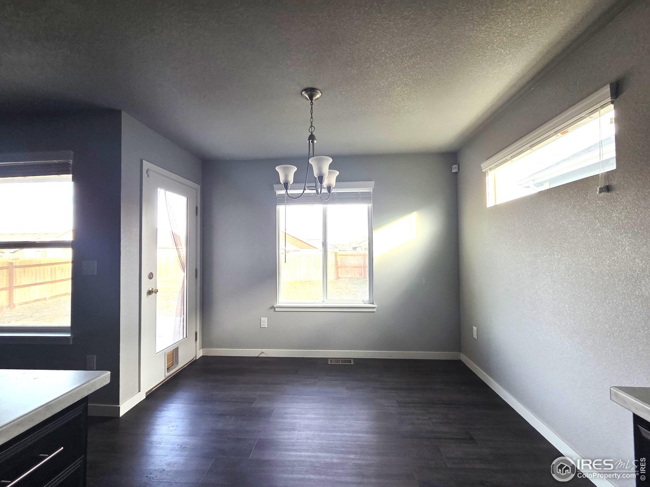 1203 Bison Way Wiggins, CO 80654 - Photo 5 of 17 an empty room with wooden floor and windows