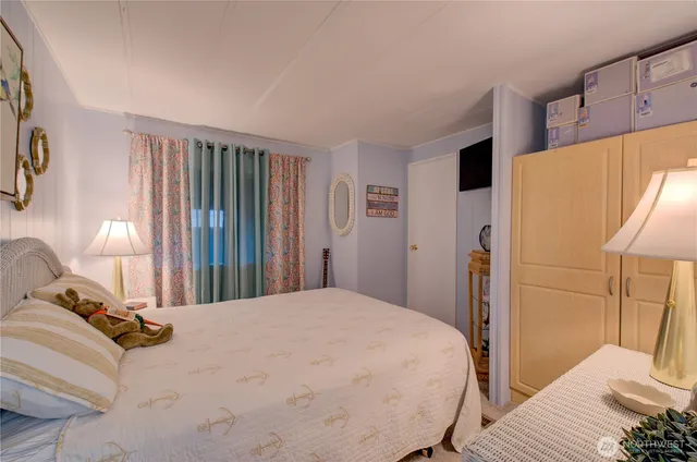 a bedroom with a bed and a lamp on dresser next to a window