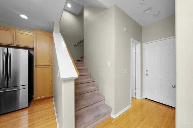 a view of a hallway with stainless steel appliances wooden floor and staircase