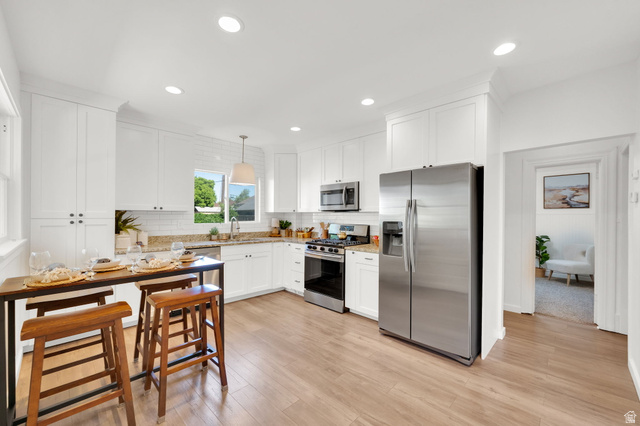 446 South 300 East Provo, UT 84606 - Photo 13 of 32 Bright kitchen featuring white shaker cabinetry, stainless steel appliances, granite countertops, wood-finish flooring, and recessed lighting