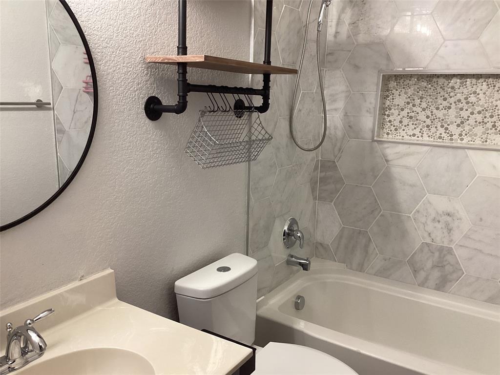 10320 Point Lobos Trail Fort Worth, TX 76177 - Photo 21 of 33 Bathroom featuring hexagon wall tiles, a built-in shower niche with mosaic tile, a white bathtub with chrome fixtures, and a wall-mounted shelving unit with wood-finish shelves and industrial pipe detailing