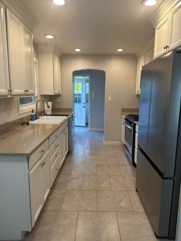 a large kitchen with a sink stainless steel appliances and cabinets
