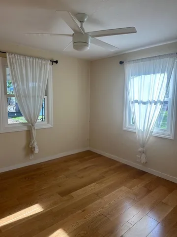 a view of an empty room with a window and wooden floor