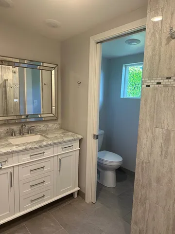 a bathroom with a granite countertop toilet sink and mirror