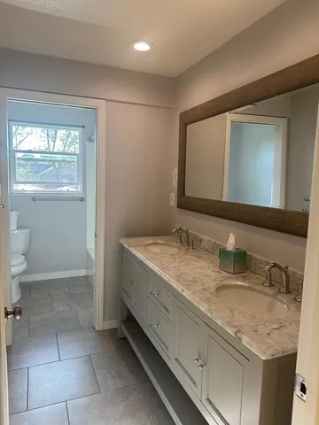 a bathroom with a granite countertop sink a toilet and a mirror