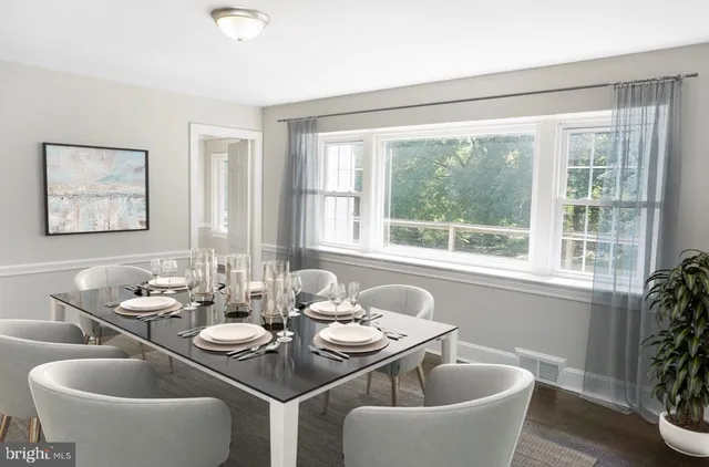 a dining room with furniture a large window and a potted plant