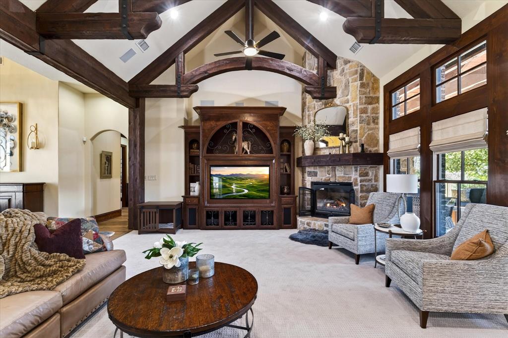 1625 Timber Ridge Trail Cross Roads, TX 76227 - Photo 14 of 40 Carpeted living room with high vaulted ceiling, a stone fireplace, beam ceiling, arched walkways, and a ceiling fan