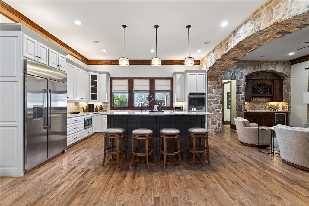 1625 Timber Ridge Trail Cross Roads, TX 76227 - Photo 21 of 40 Kitchen with decorative light fixtures, a kitchen island with sink, a kitchen bar, built in appliances, and glass insert cabinets