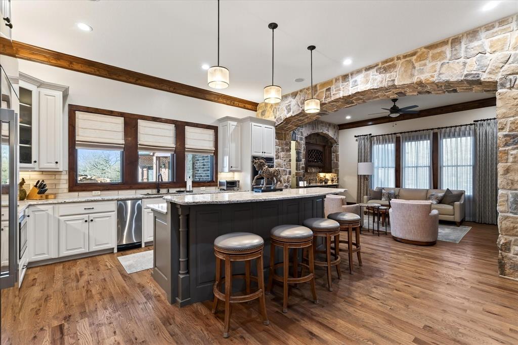 1625 Timber Ridge Trail Cross Roads, TX 76227 - Photo 22 of 40 Kitchen with ornamental molding, light stone countertops, white cabinetry, a center island with sink, and decorative light fixtures