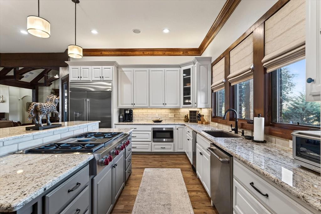 1625 Timber Ridge Trail Cross Roads, TX 76227 - Photo 24 of 40 Kitchen with hanging light fixtures, light stone countertops, gray cabinetry, dark wood-type flooring, and ornamental molding