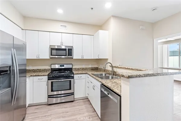 a kitchen with stainless steel appliances granite countertop a stove a refrigerator and a microwave
