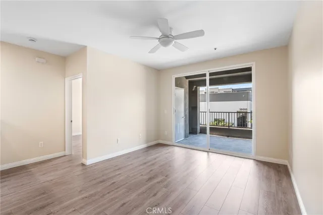 an empty room with wooden floor fan and windows