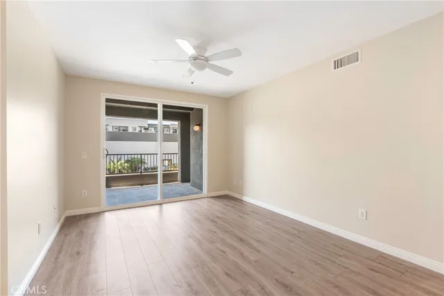 an empty room with wooden floor fan and windows