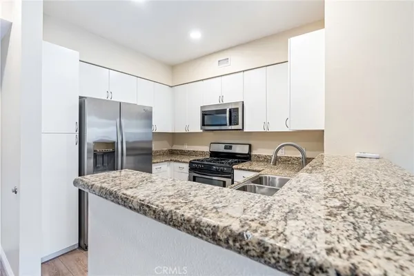 a kitchen with stainless steel appliances granite countertop a refrigerator a stove a sink a stove a microwave and a refrigerator