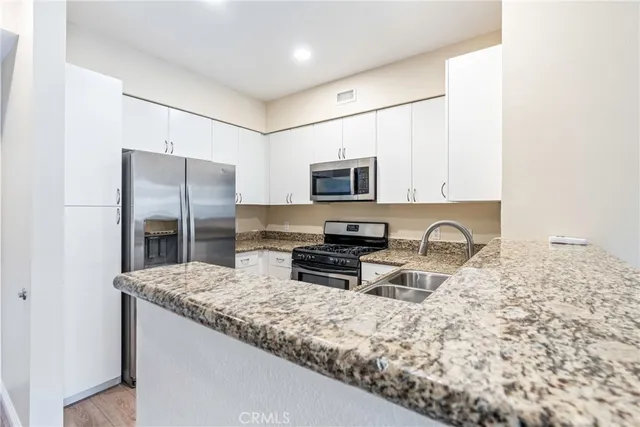 a kitchen with stainless steel appliances granite countertop a refrigerator a stove a sink a stove a microwave and a refrigerator