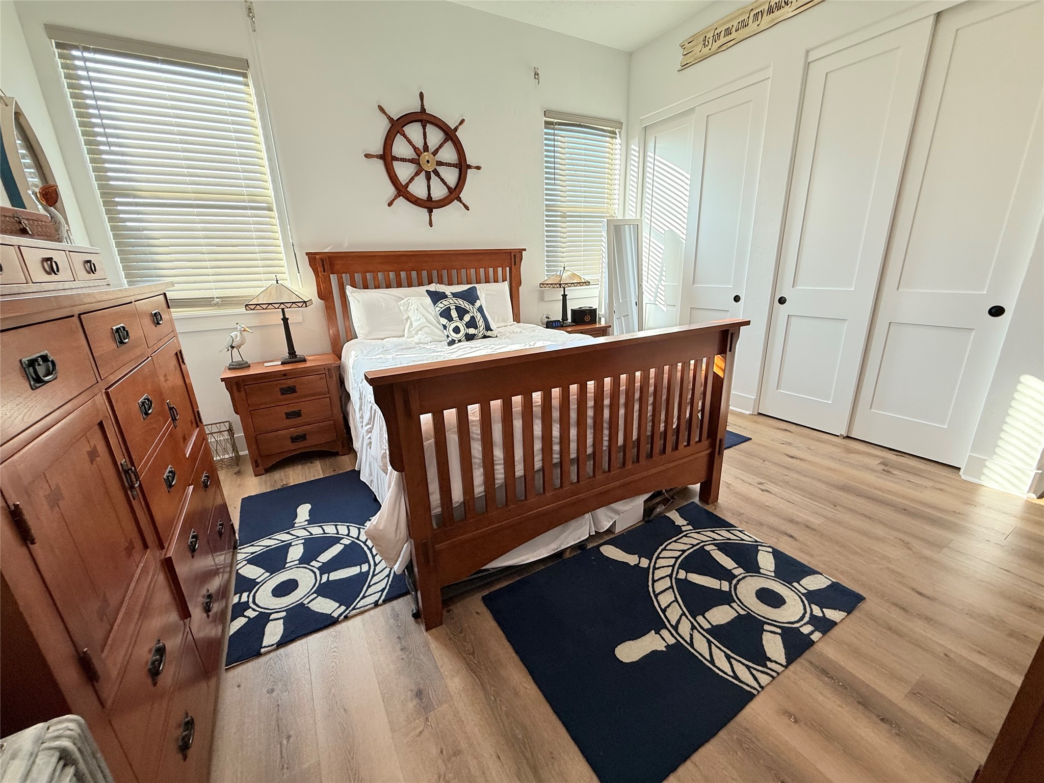 2023 County Road 201 Sargent, TX 77414 - Photo 22 of 45 This bedroom features a nautical theme with elegant wood furniture, a ship wheel wall decor, and matching navy rugs. It has large windows for ample natural light, a comfortable bed, and spacious closets. Perfect for a serene and stylish retreat.