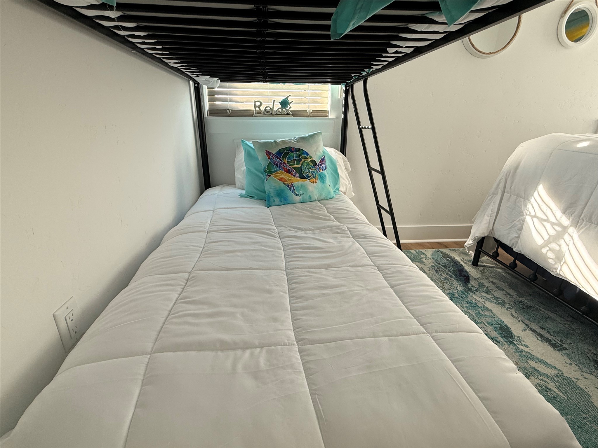 2023 County Road 201 Sargent, TX 77414 - Photo 26 of 45 This cozy bedroom features a bunk bed setup with a colorful pillow, soft white bedding, and a nearby window for natural light. Perfect for a child’s room or guest space.