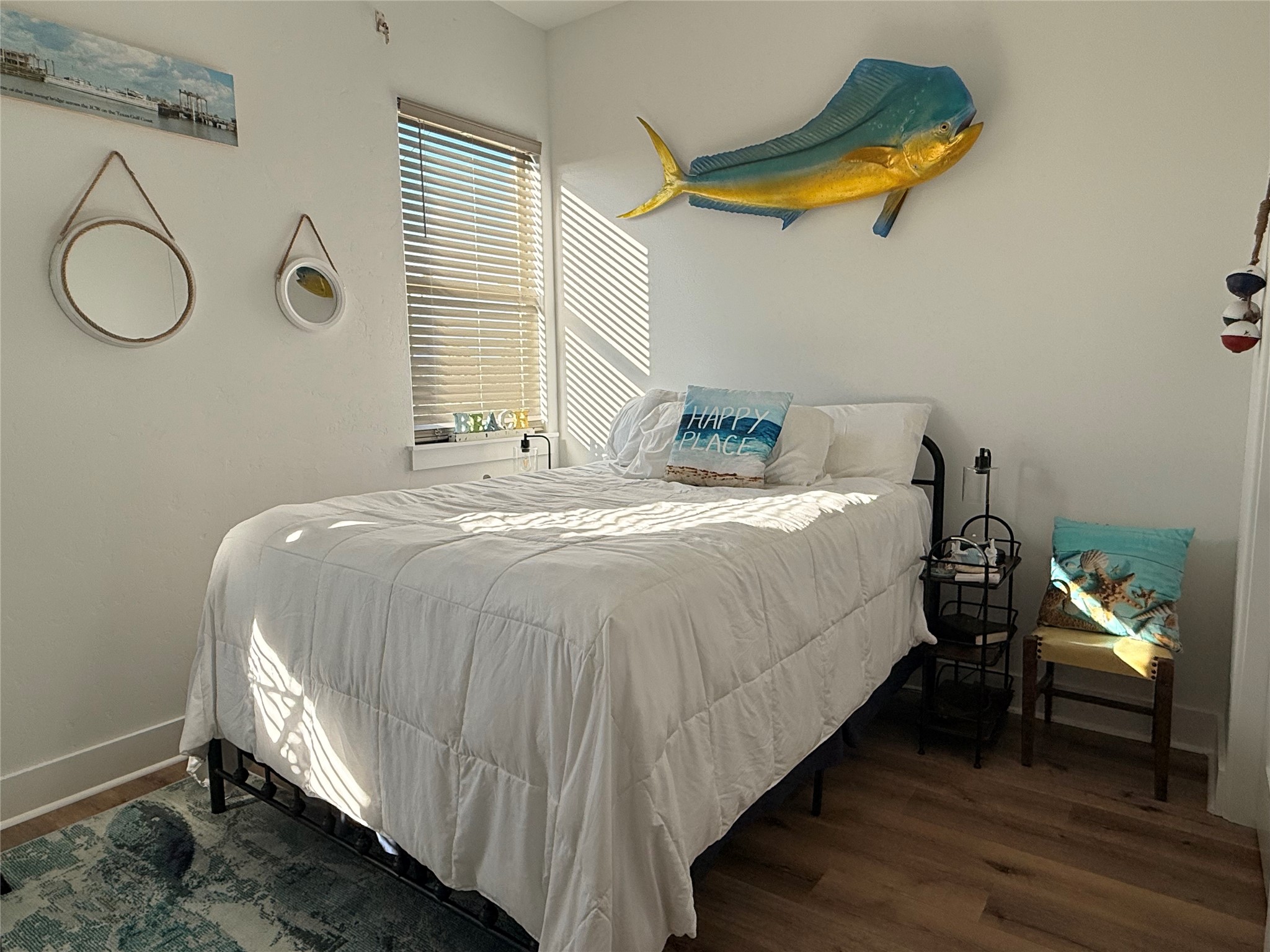2023 County Road 201 Sargent, TX 77414 - Photo 27 of 45 Bright and cozy bedroom with a nautical theme, featuring a double bed, coastal decor, and abundant natural light from a window with blinds.