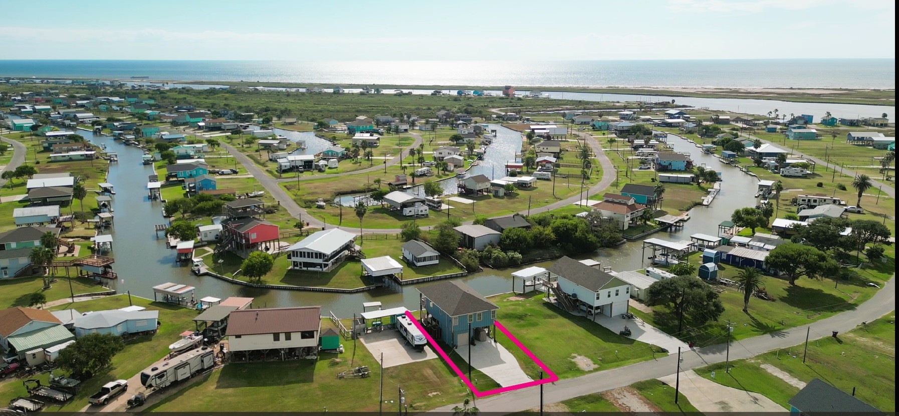 2023 County Road 201 Sargent, TX 77414 - Photo 5 of 45 This aerial photo showcases this coastal neighborhood with canal-front homes, ideal for boating and fishing enthusiasts. The highlighted property is a modern, elevated house with direct water access, offering scenic water views and proximity to the Gulf and East Matagorda Bay. Perfect for those seeking a serene, waterfront lifestyle.