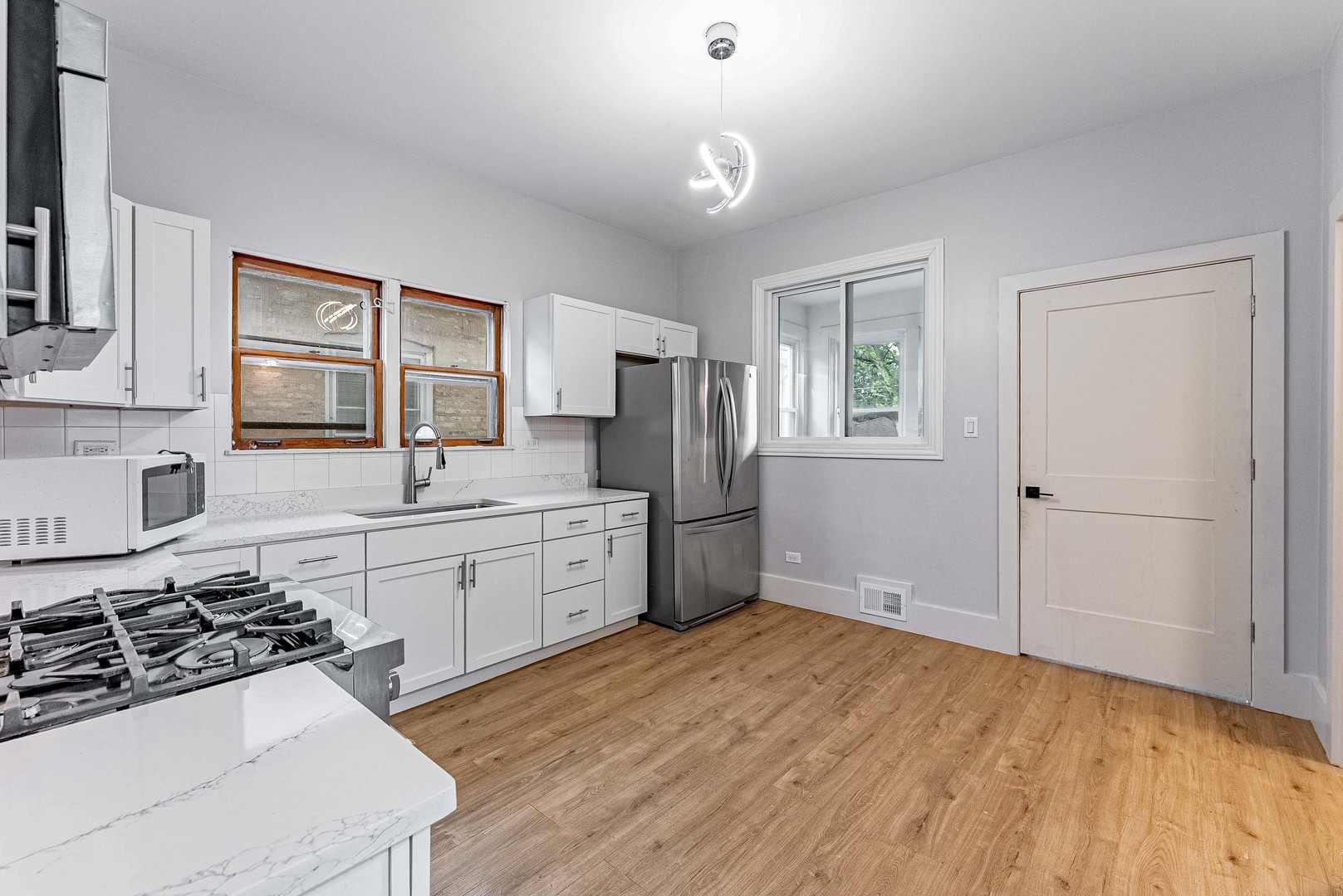 1330 Ridgeland Avenue Berwyn, IL 60402 - Photo 9 of 23 a kitchen with granite countertop a stove a sink dishwasher a refrigerator and white cabinets with wooden floor