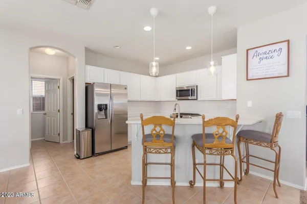 a kitchen with stainless steel appliances kitchen island granite countertop a refrigerator and a dining table