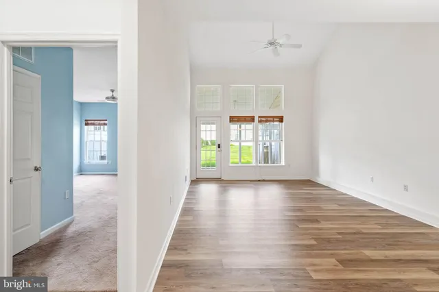 a view of an empty room with window and wooden floor