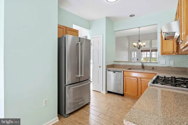 a kitchen with granite countertop stainless steel appliances a refrigerator and stove top oven