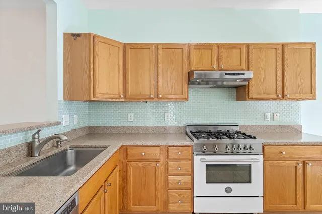a kitchen with granite countertop a sink stove and cabinets