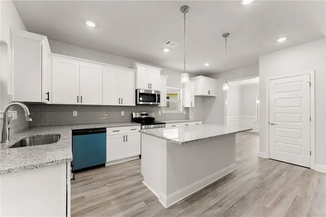 a kitchen with kitchen island a sink stainless steel appliances and cabinets