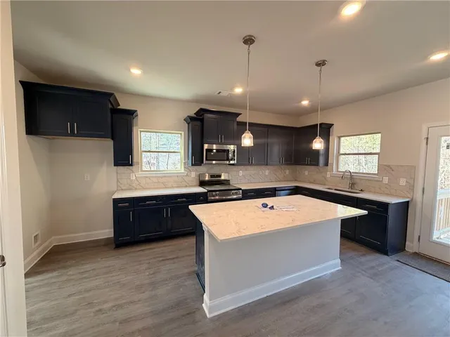 a large kitchen with kitchen island a sink dishwasher a stove and a refrigerator with wooden floor