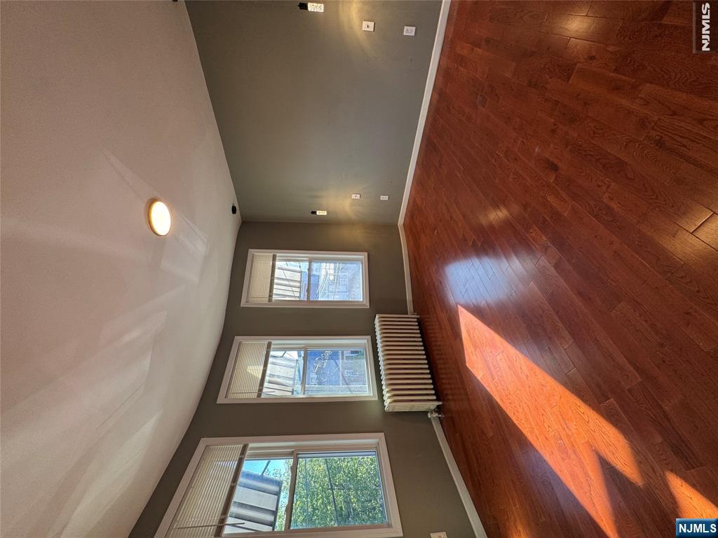 307 Henry Street, Unit 2 Fairview, NJ 07022 - Photo 4 of 10 an empty room with wooden floor and windows