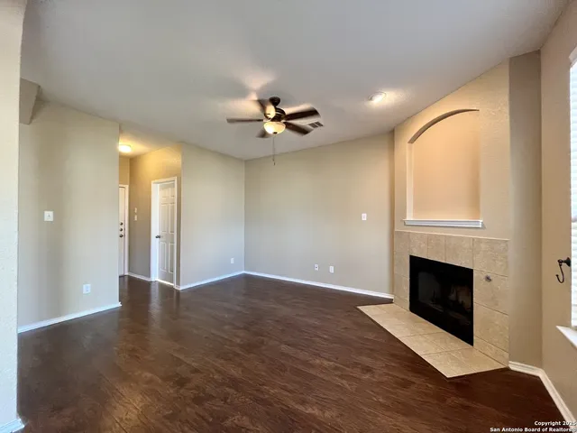 a view of an empty room with wooden floor and a fireplace