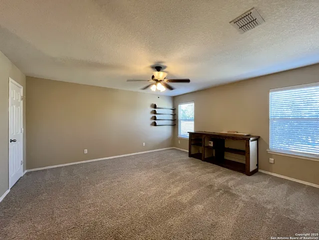 a view of an empty room with a chandelier fan