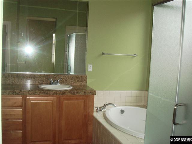 1045 South University Park Loop Reno, NV 89512 - Photo 8 of 9 a bathroom with a granite countertop sink a mirror and a bathtub