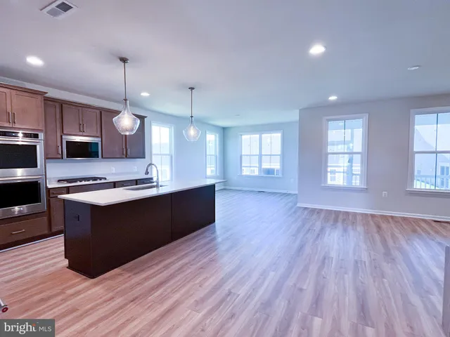 a large kitchen with stainless steel appliances granite countertop a large counter top and wooden floors