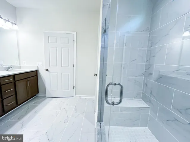 a bathroom with a granite countertop sink and a shower