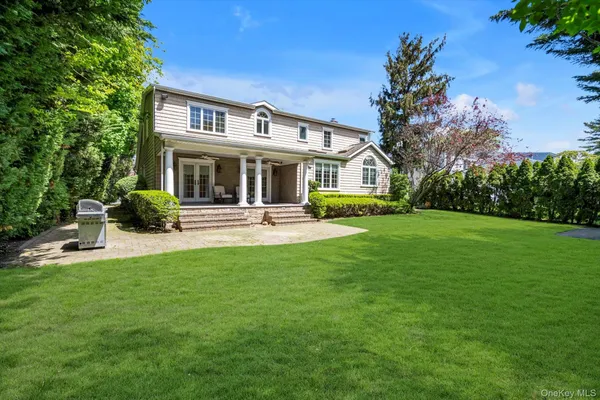 a front view of a house with garden and trees