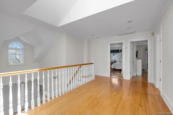 a view of a hallway with wooden floor and a bathroom