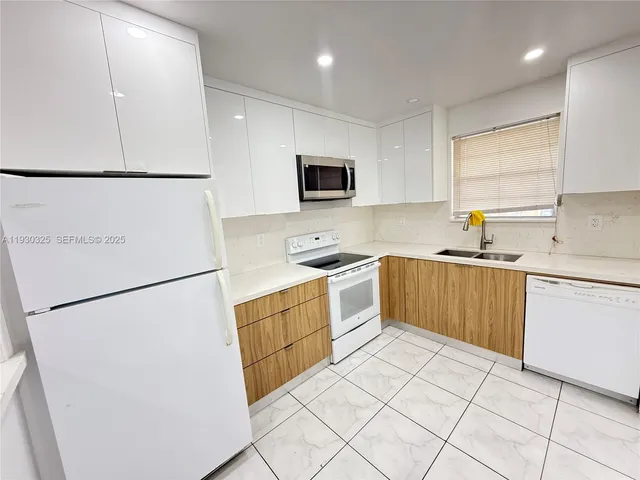 a kitchen with a sink a refrigerator a microwave and cabinets