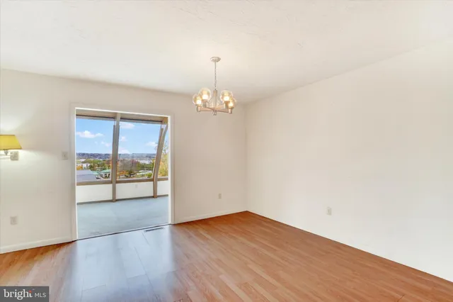 a view of empty room with wooden floor and window