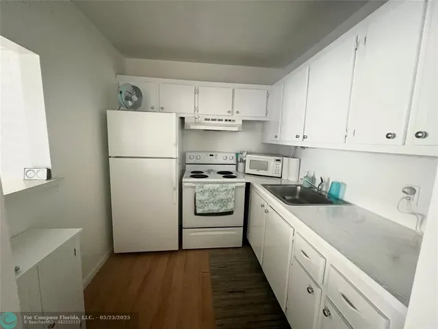 a kitchen with white cabinets and white appliances