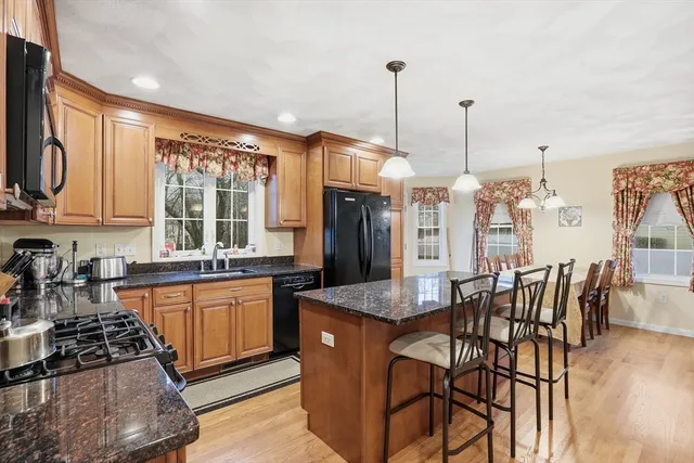 a kitchen with stainless steel appliances granite countertop a stove top oven a sink a dining table and chairs with wooden floor