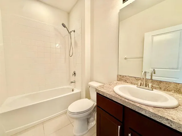 a bathroom with a granite countertop sink a toilet and shower
