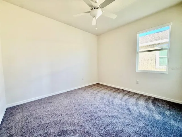 an empty room with a window and a fan