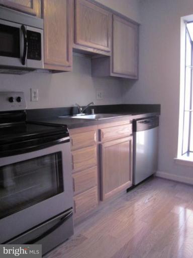 35 Andrew Place, Unit R112 Baltimore, MD 21201 - Photo 6 of 20 a kitchen with stainless steel appliances granite countertop a stove a microwave and a white cabinets