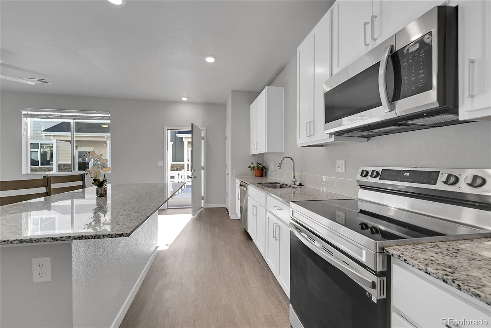 1353 Reynolds Street, Unit 3C Fort Lupton, CO 80621 - Photo 8 of 31 a kitchen with stainless steel appliances granite countertop a stove microwave and sink