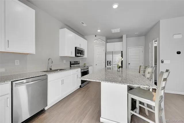 a large kitchen with granite countertop a large counter top appliances and cabinets