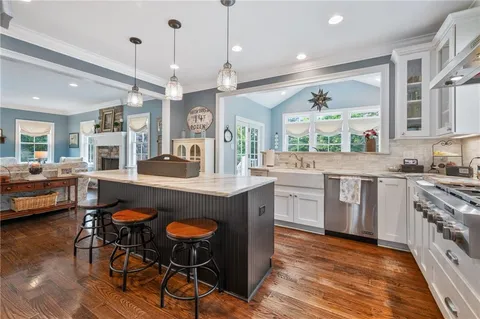 a kitchen with stainless steel appliances granite countertop a stove a sink dishwasher a dining table and chairs with wooden floor