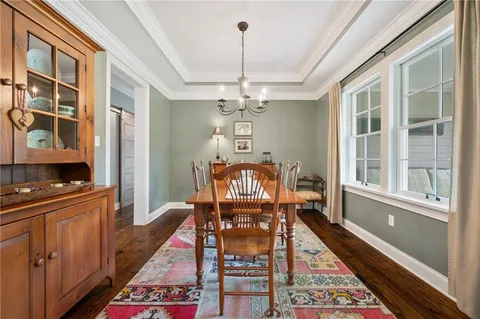 a dining room with wooden floor a chandelier a wooden table and chairs
